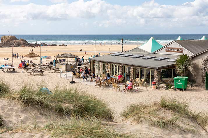 People sit outside the cafe in the sand