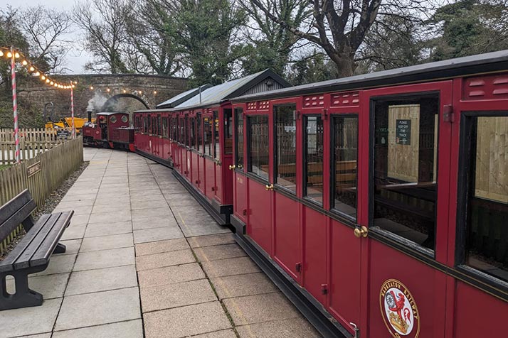 red train at lappa valley station with bridge and fairy lights